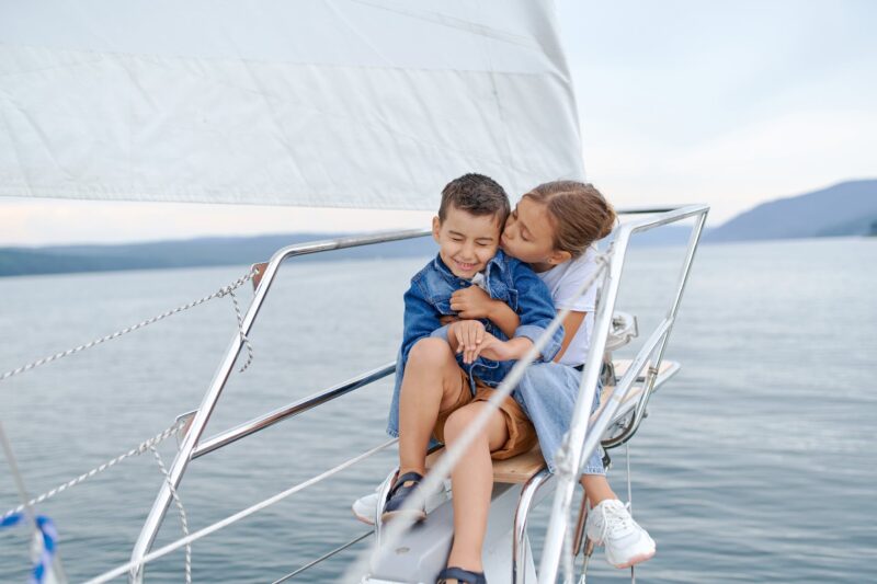 little girl kissing brother on sailboat