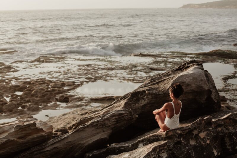 photo of woman sitting on rock