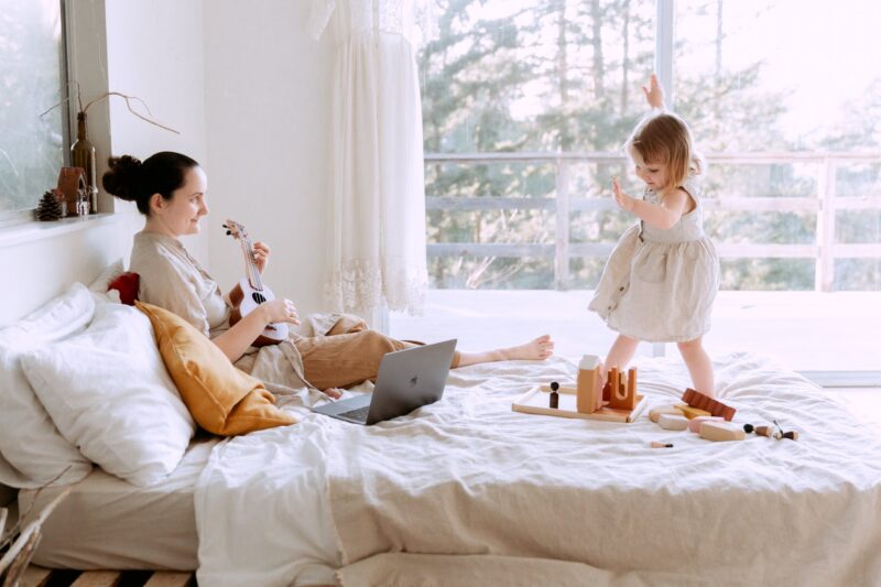 happy young woman playing ukulele for daughter at home
